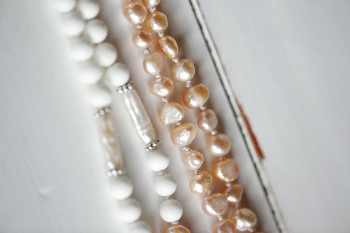 Strands of cream and pink cultured pearls laid out for grading on a white surface