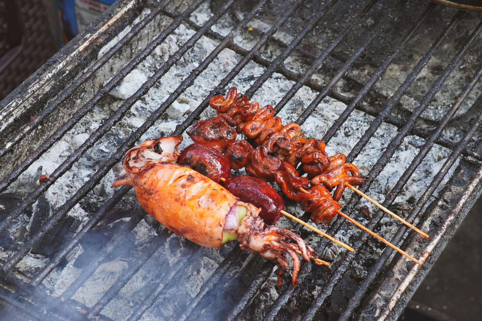 Seafood skewers grilling over charcoal at an open-air kitchen, the kind of BBQ counter found along the Sonasea food street